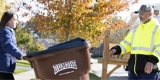 Garbage collector with young girl putting out garbage can