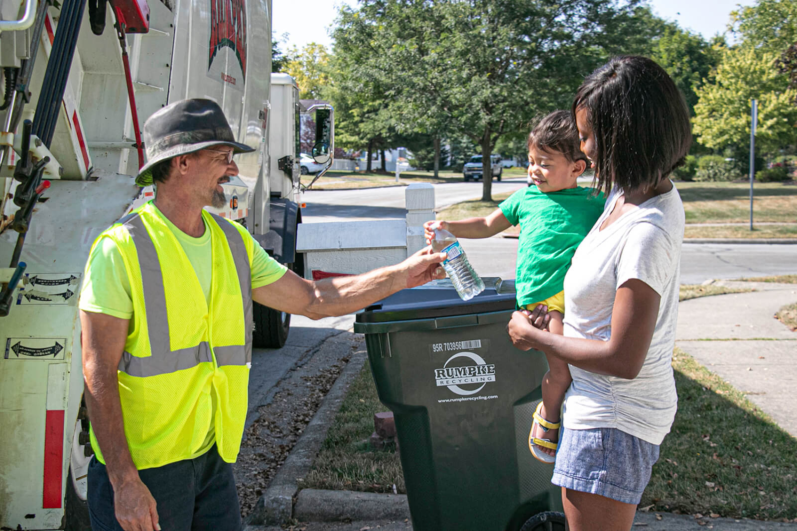 Rumpke Driver With Residents Picking Up Recycling Cart Along Curb